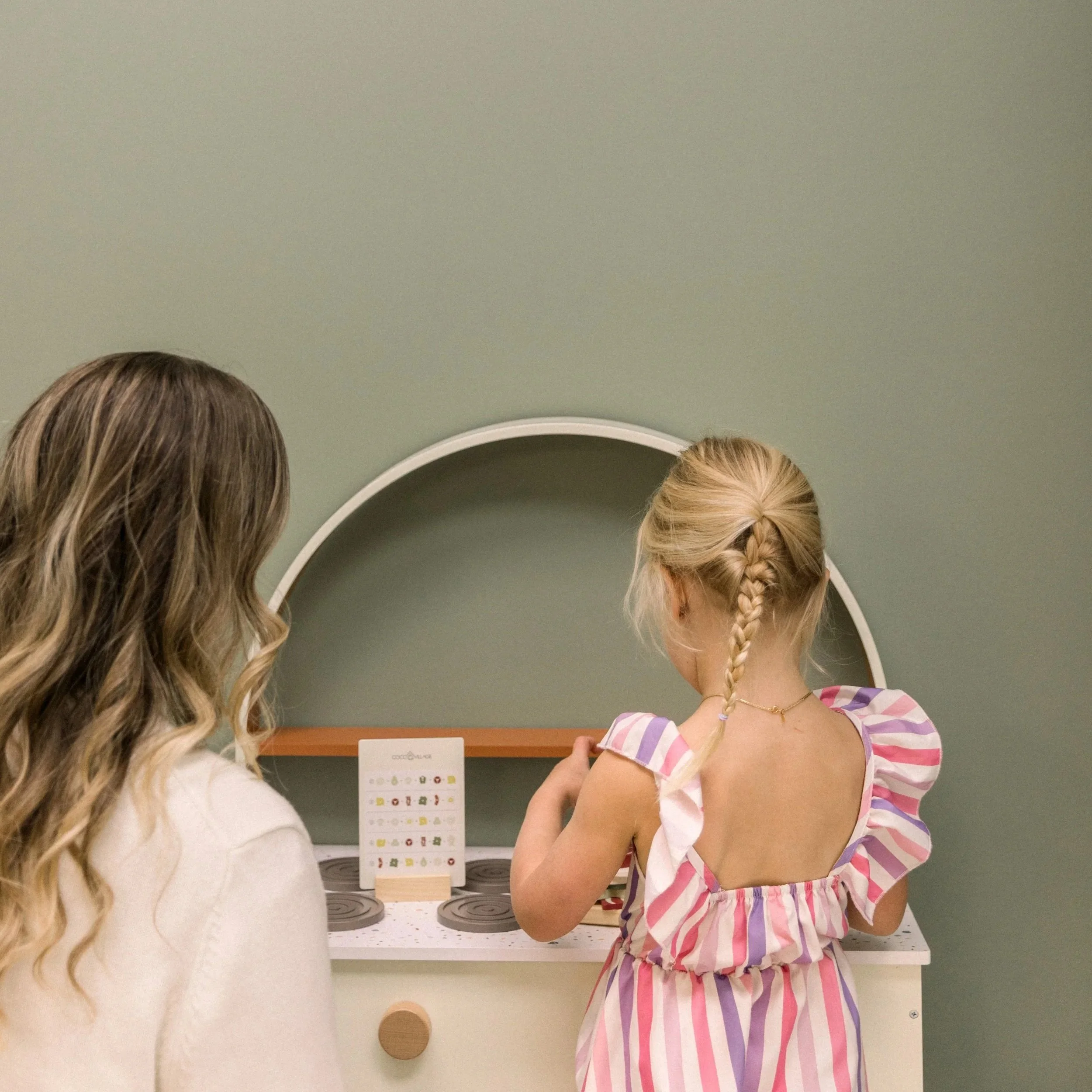 Play-based speech therapy - The speech therapist is playing in the Coco Village play kitchen with a young girl.