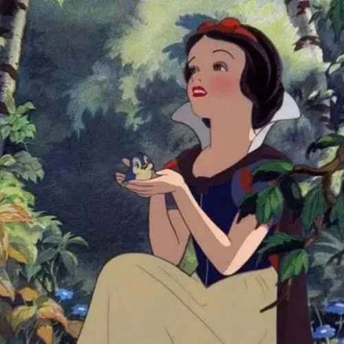 Snow White sitting in a forest, holding a small bird, surrounded by greenery.