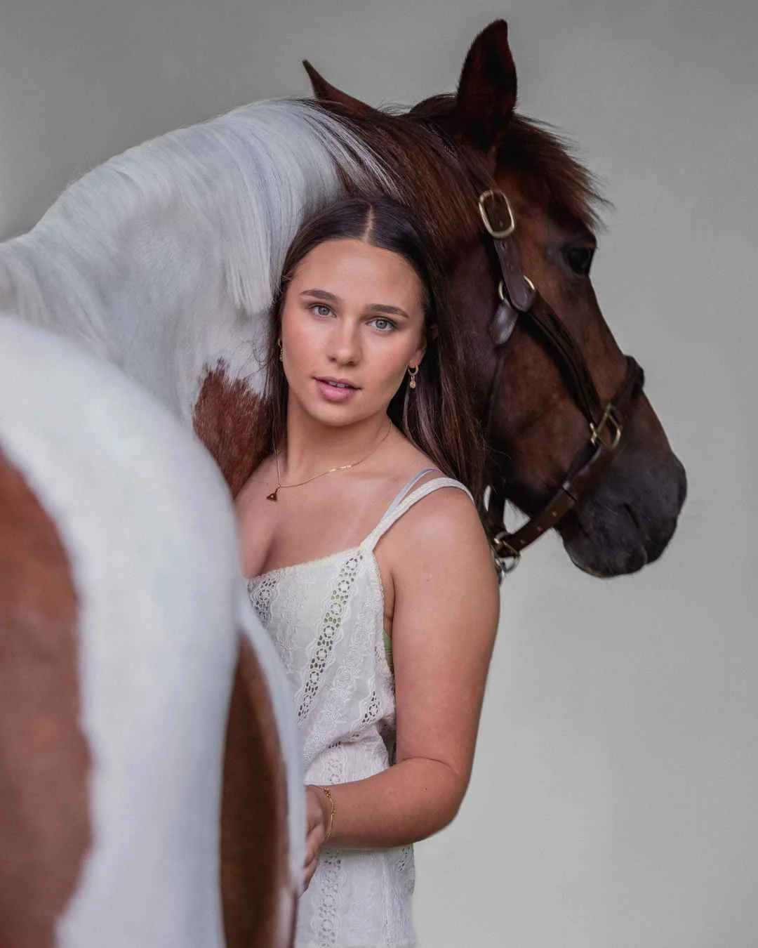 new zealand equine photographer of A woman standing beside a horse, holding the horse's bridle, with both facing the camera.