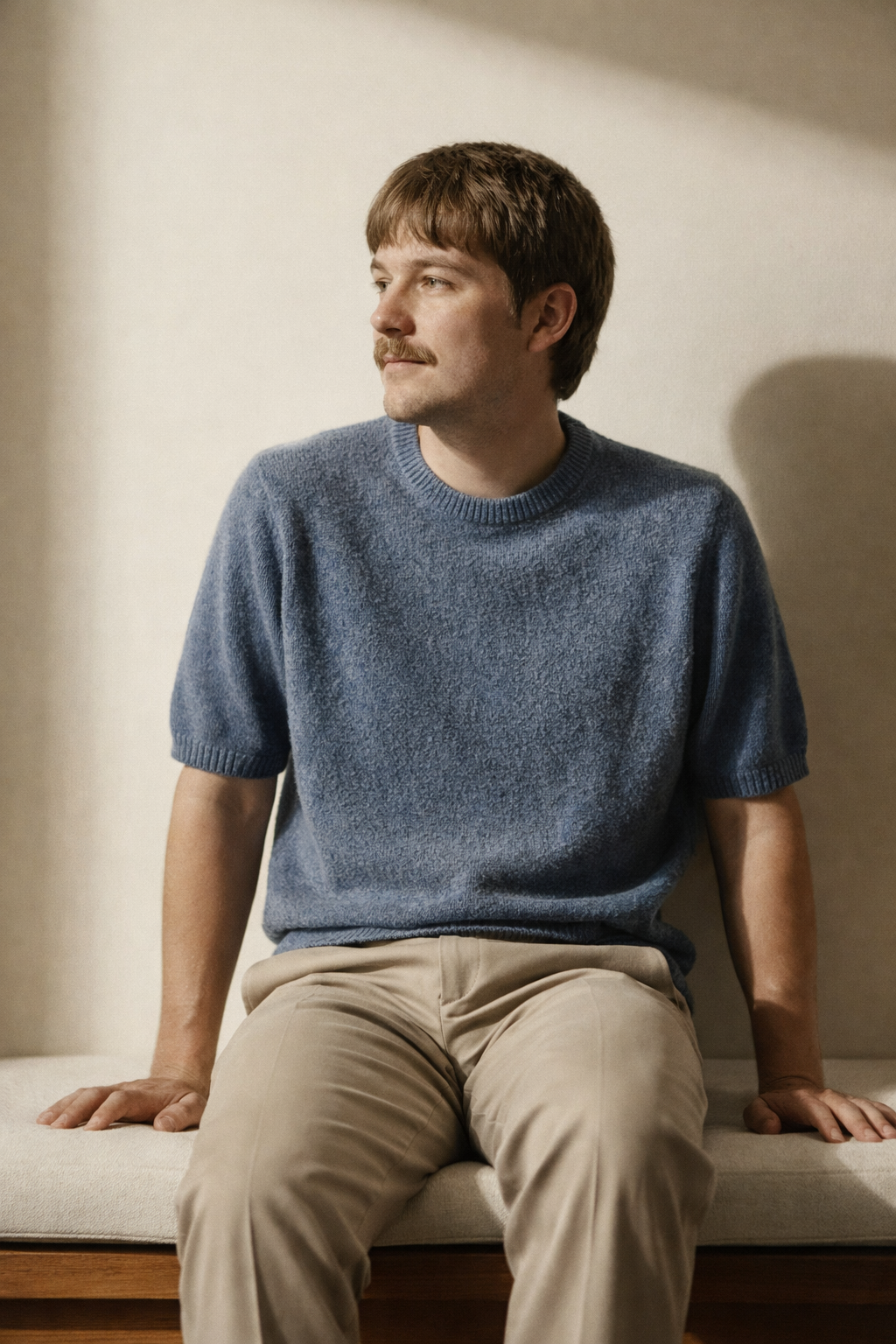 A young man with brown hair sitting on a benchseat