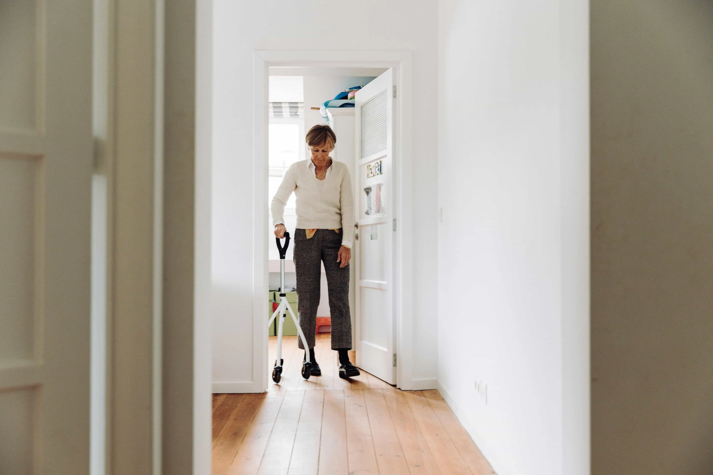 A woman in a doorway, using a walker to assist her movement.