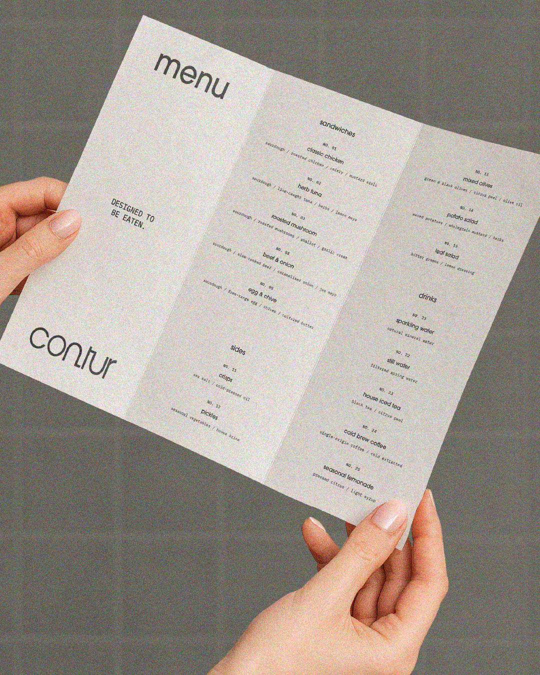 A person holding a three-paneled menu of 'contur'.