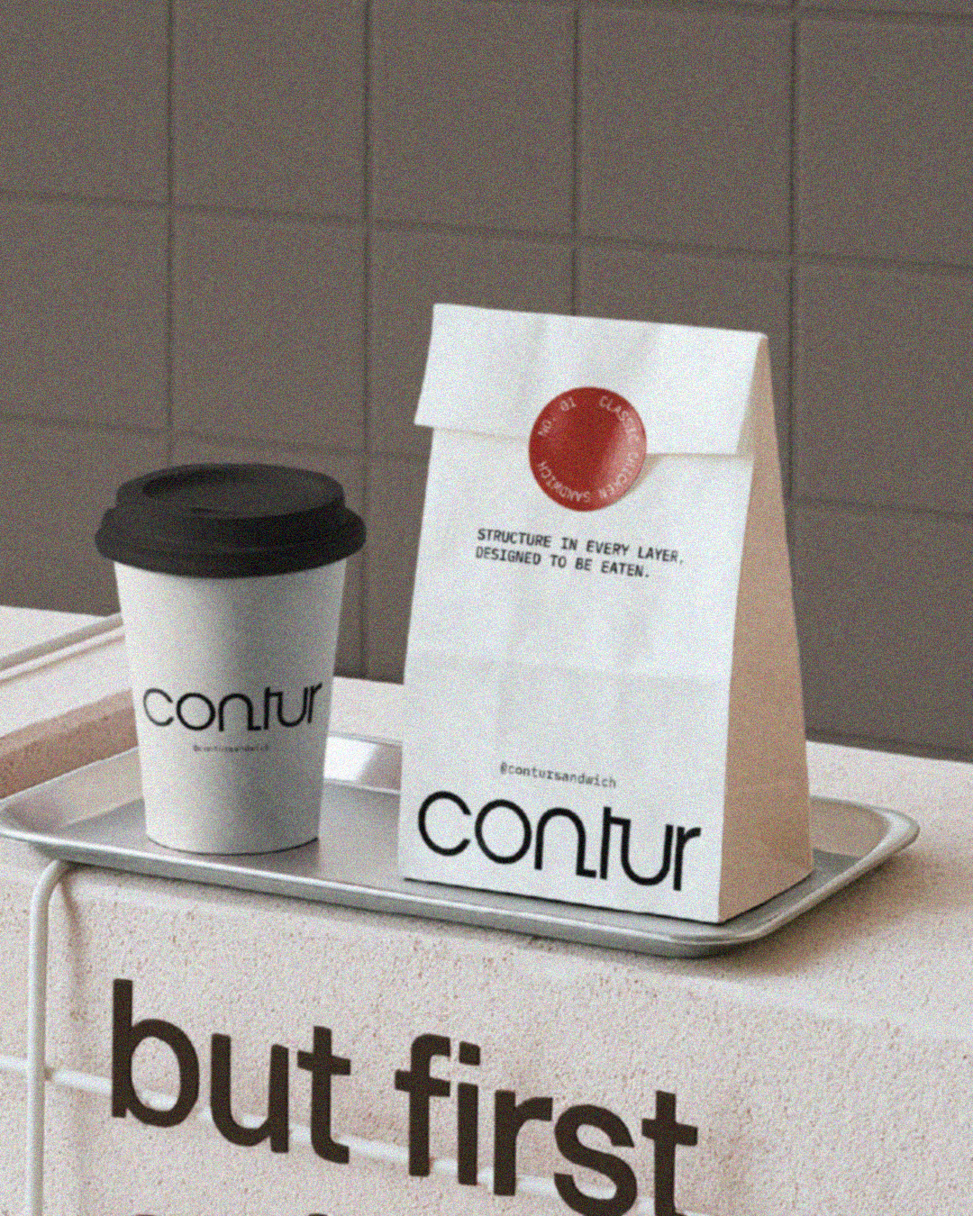 A white paper bag and a paper coffee cup with black text that reads 'CONTUR'