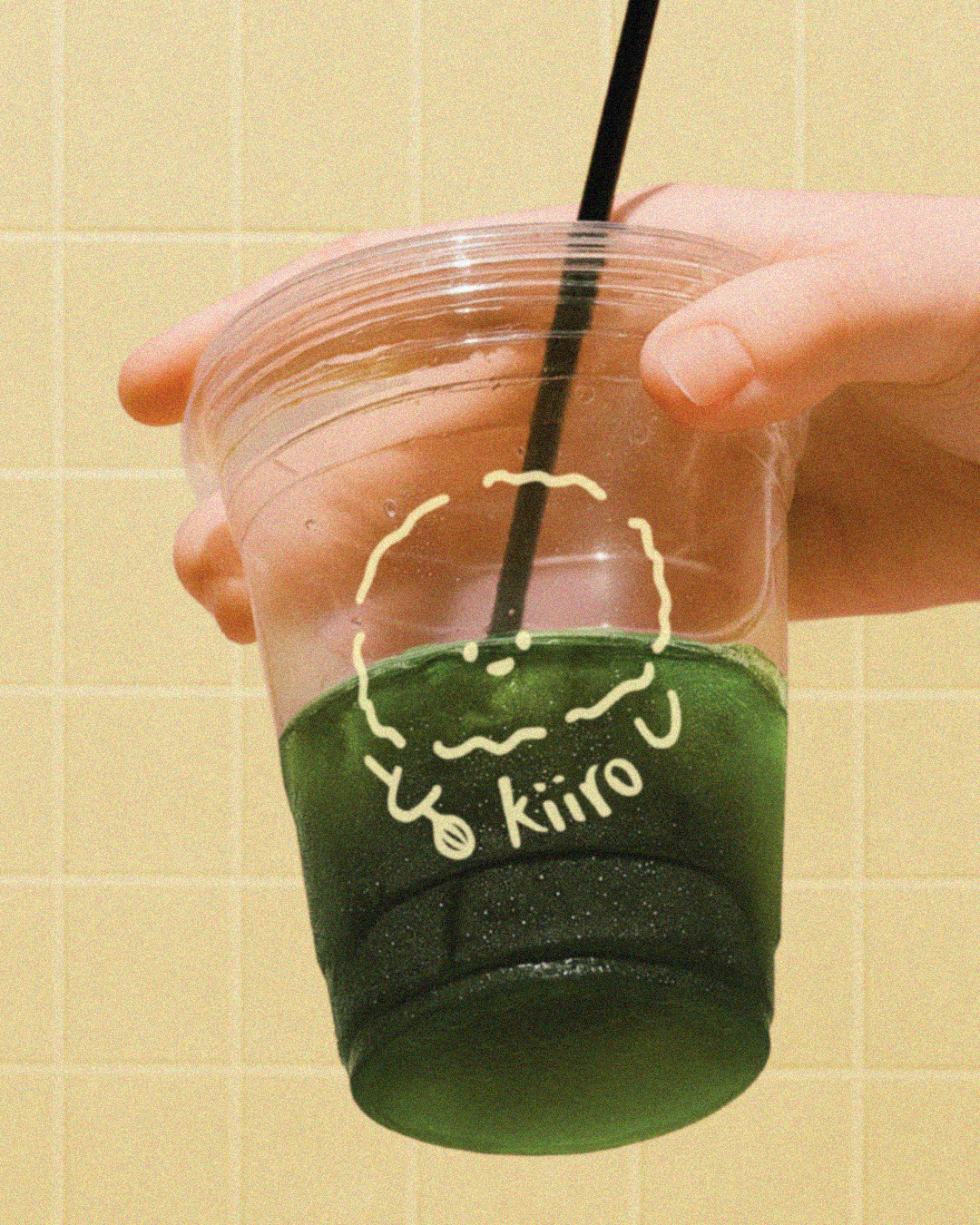 A hand holding a matcha cup with the logo 'kiiro' on the cup.