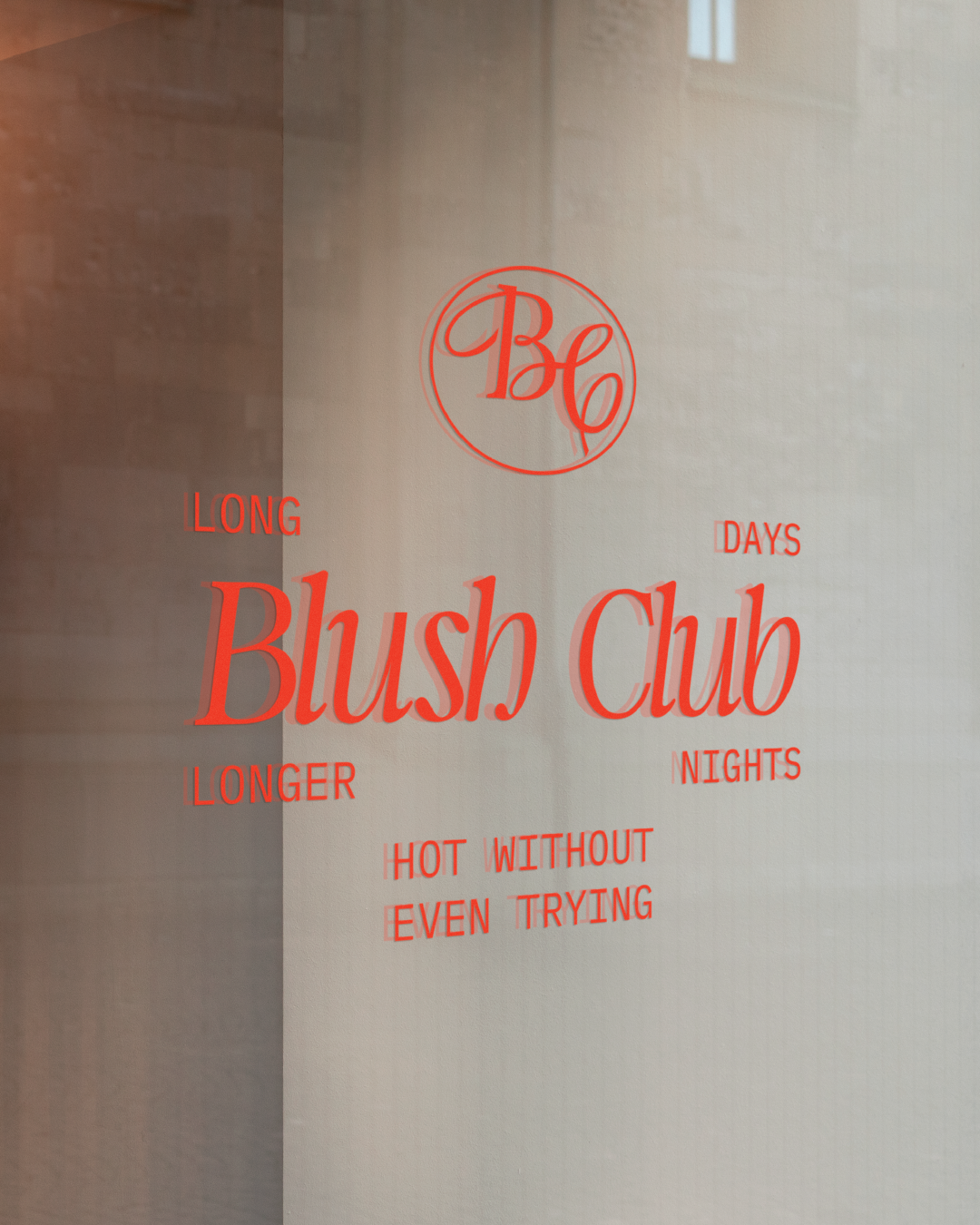 Glass window with orange logo of 'Blush Club'