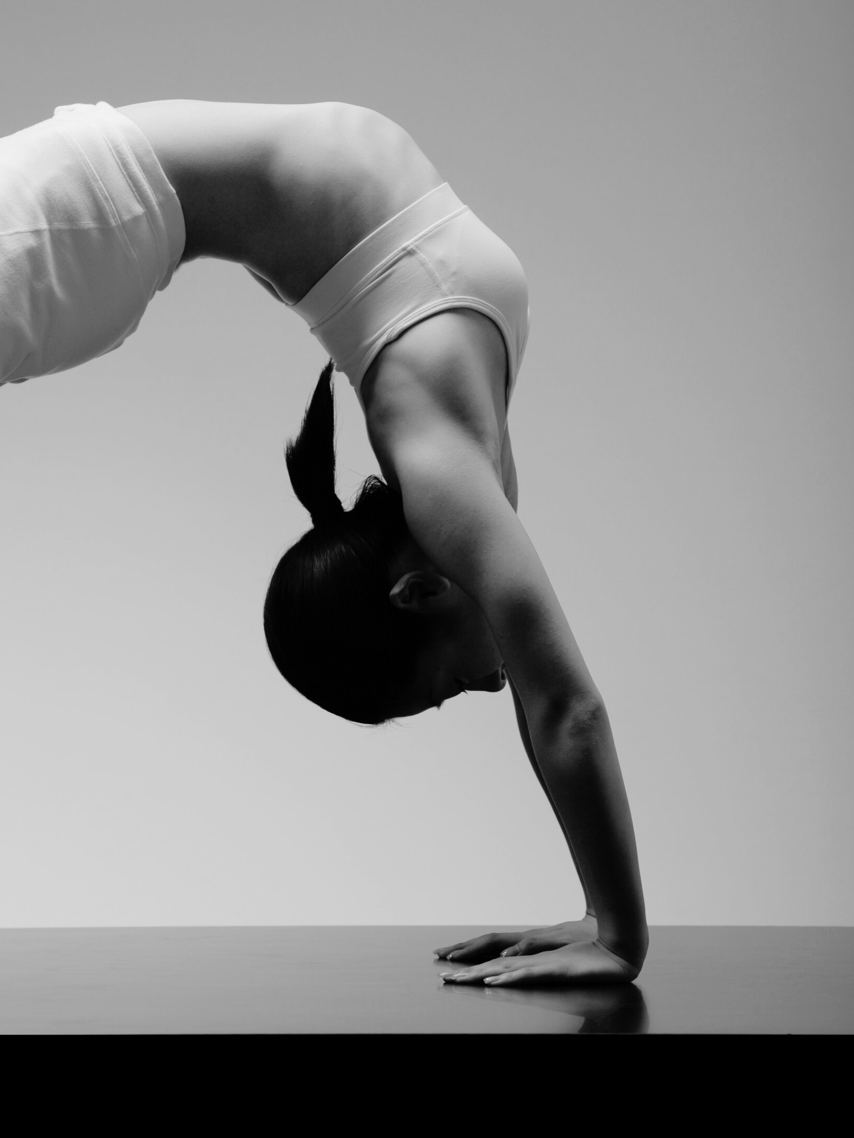 A person doing a yoga pose in a downward dog position, with their head facing downward and hands on the ground.