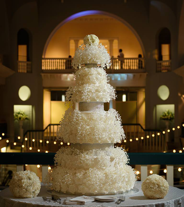 Five tier luxury wedding cake with intricate sugar flowers displayed at an elegant wedding venue