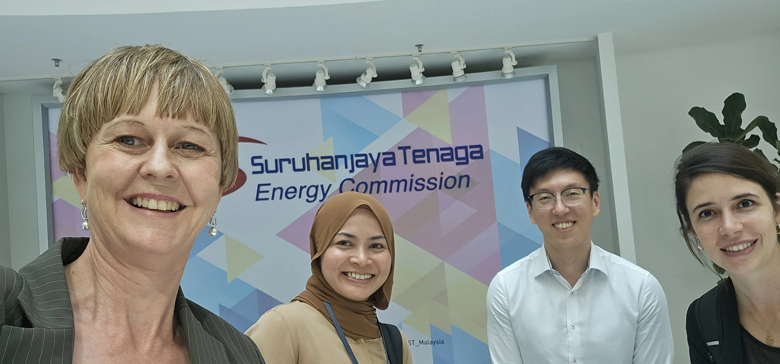 Dr Gabrielle Kuiper and colleagues in front of a sign for the Suruhanjaya Tenaga Energy Commission in Malaysia.