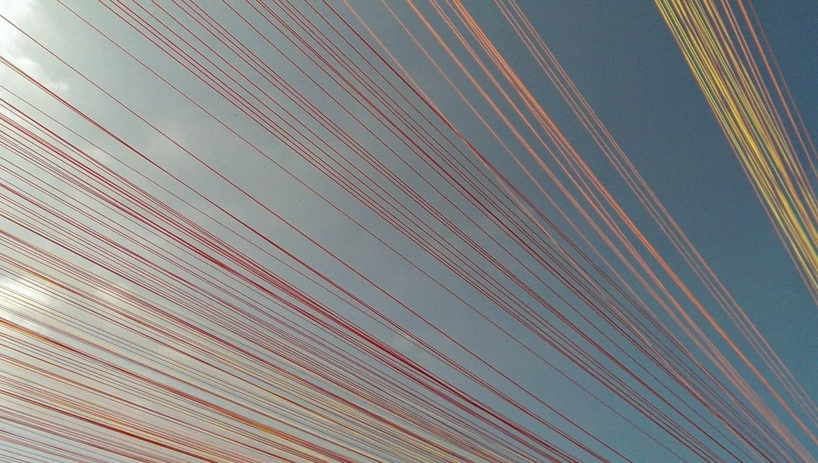 Close-up of colorful strands against a blue background. Art installation used figuratively to represent 'wires'
