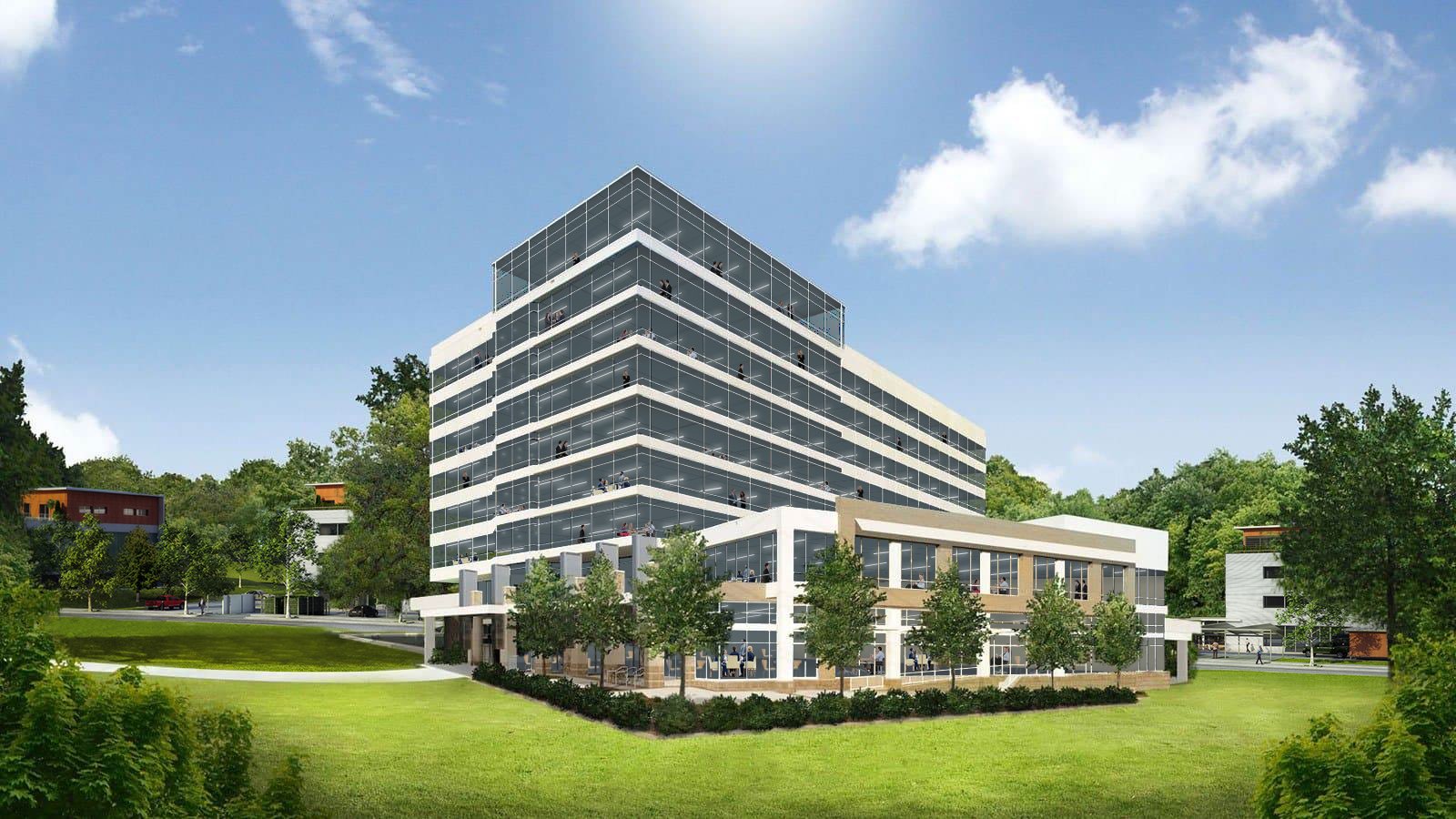 A modern multi-story office building with large glass windows, surrounded by green trees and a well-maintained lawn, under a partly cloudy sky.