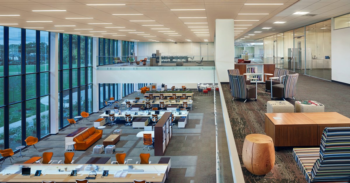 Modern, open-concept office space with large windows, multiple workstations, and lounge areas.