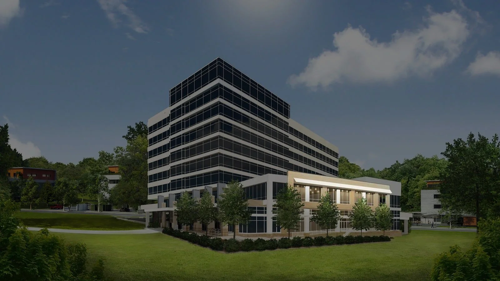 Modern multi-story office building with extensive glass windows, surrounded by greenery and trees, under a partly cloudy sky.