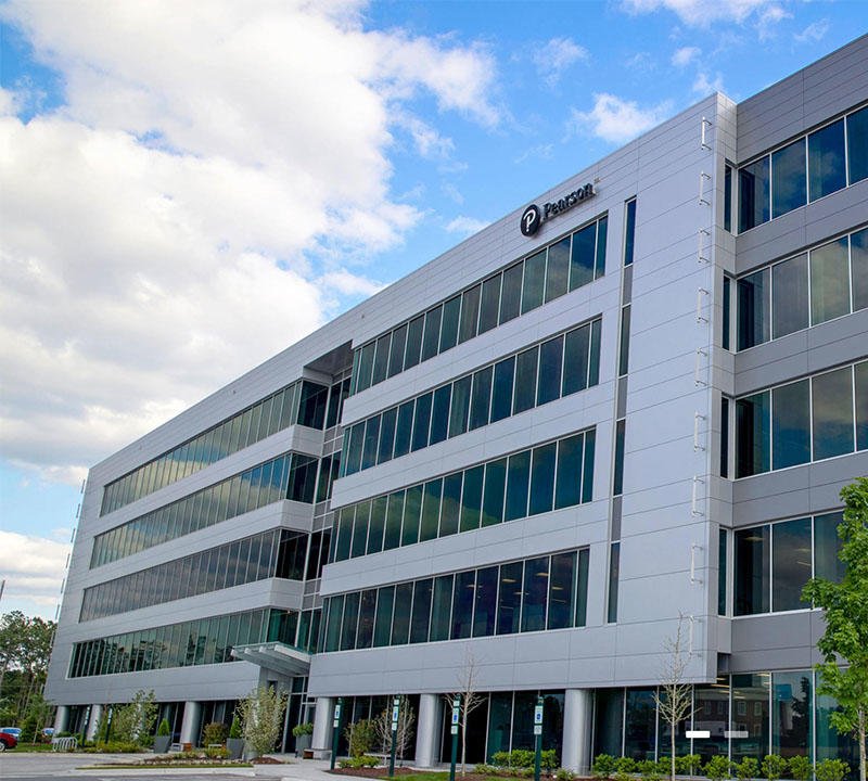 Modern multi-story office building with large glass windows and white exterior, featuring a parking sign on the top corner.