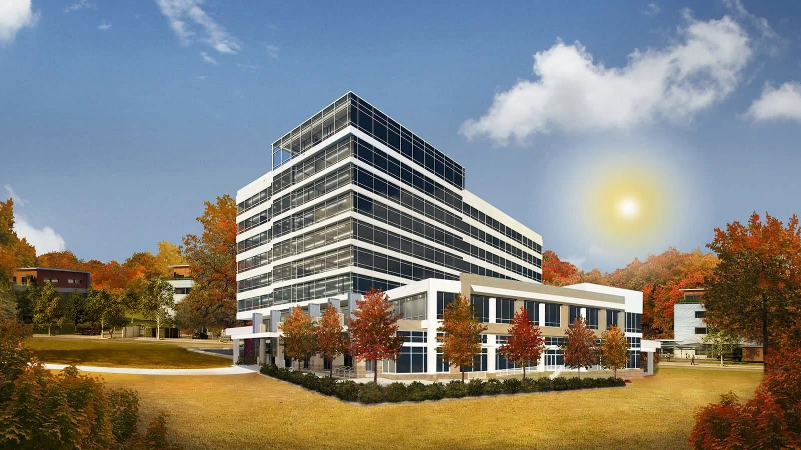 Modern multi-story office building with glass exterior, surrounded by autumn-colored trees and a grassy landscape under a blue sky with clouds and a bright sun.
