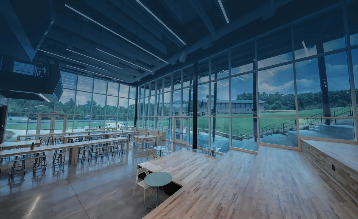 Empty modern lounge or meeting space with large floor-to-ceiling windows overlooking a grassy outdoor area and trees.