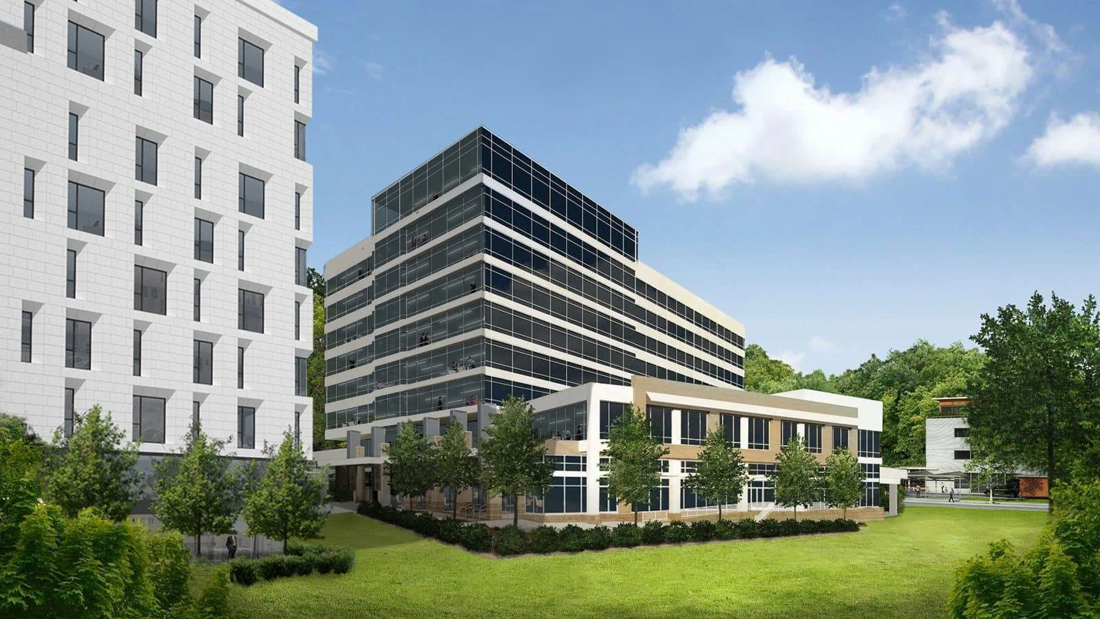Modern multi-story office building with large glass windows, surrounded by green lawns, trees, and a clear blue sky.