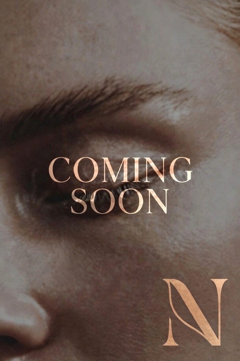 Close-up of a person's eye and eyebrow with the words 'Coming Soon' and a partial letter 'N' overlayed.