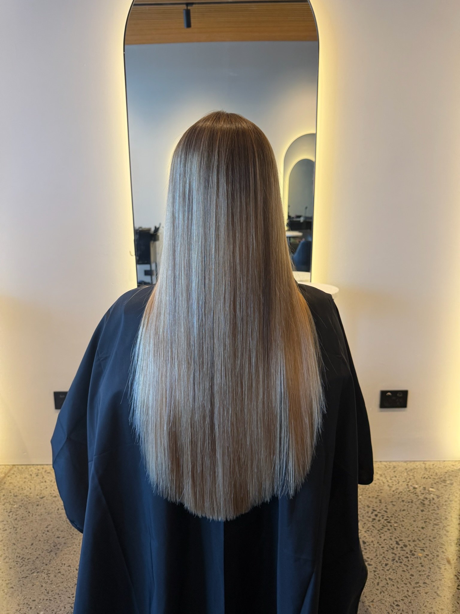 Long smooth blonde hair after Nanoplasty hair straightening treatment at Straight & Sleek salon.