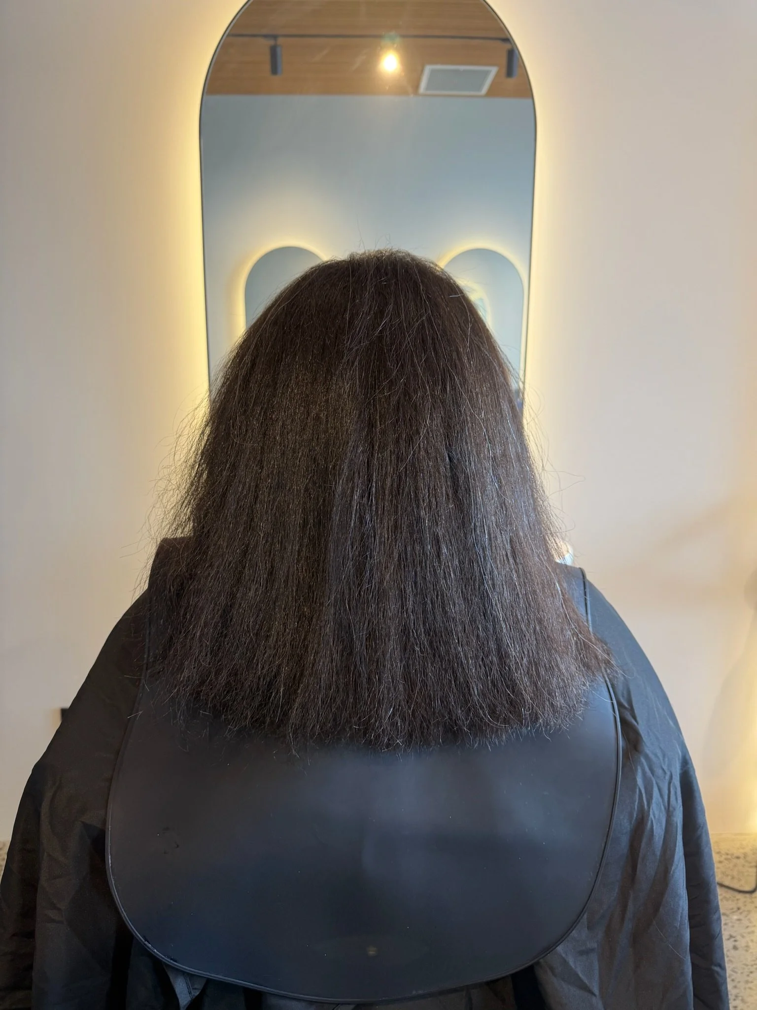 .Before Nanoplasty hair straightening showing frizzy dark hair prior to treatment at Straight & Sleek salon