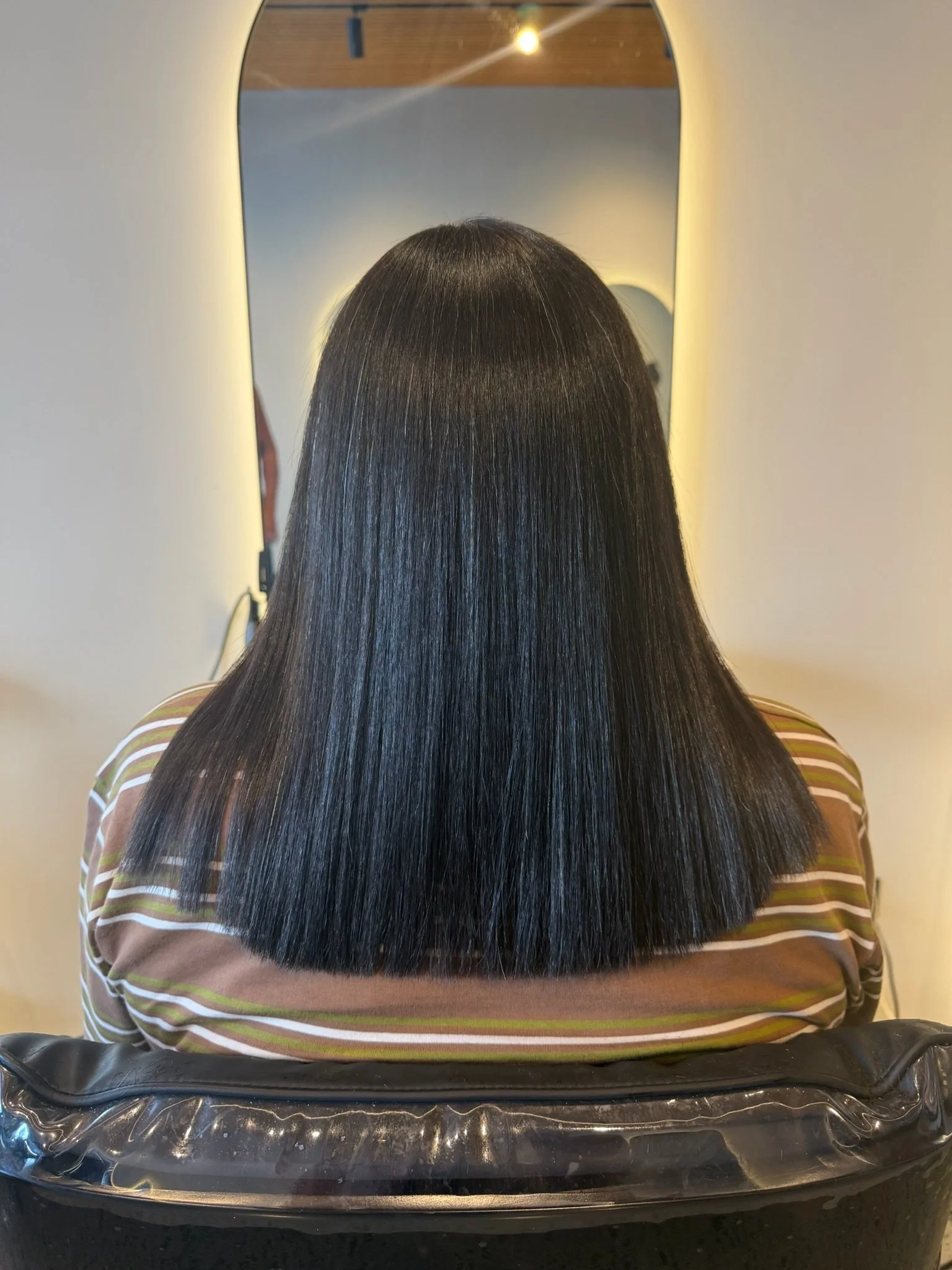 After Nanoplasty hair straightening showing smooth sleek dark hair result at Straight & Sleek salon.