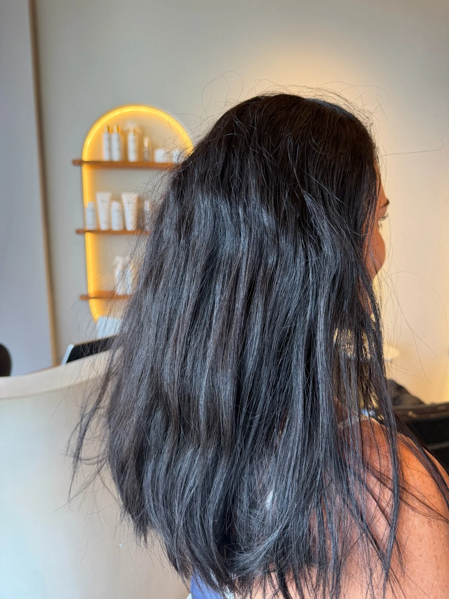 Before Nanoplasty hair straightening showing frizzy wavy dark hair prior to treatment at Straight & Sleek salon.