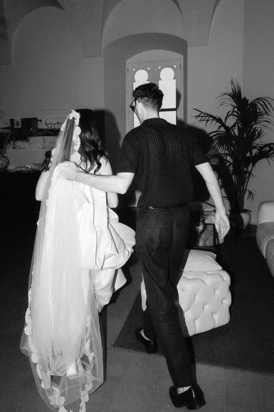 A bride with a veil and Alex Morabito the wedding planning guiding her through her wedding day captured in black and white.
