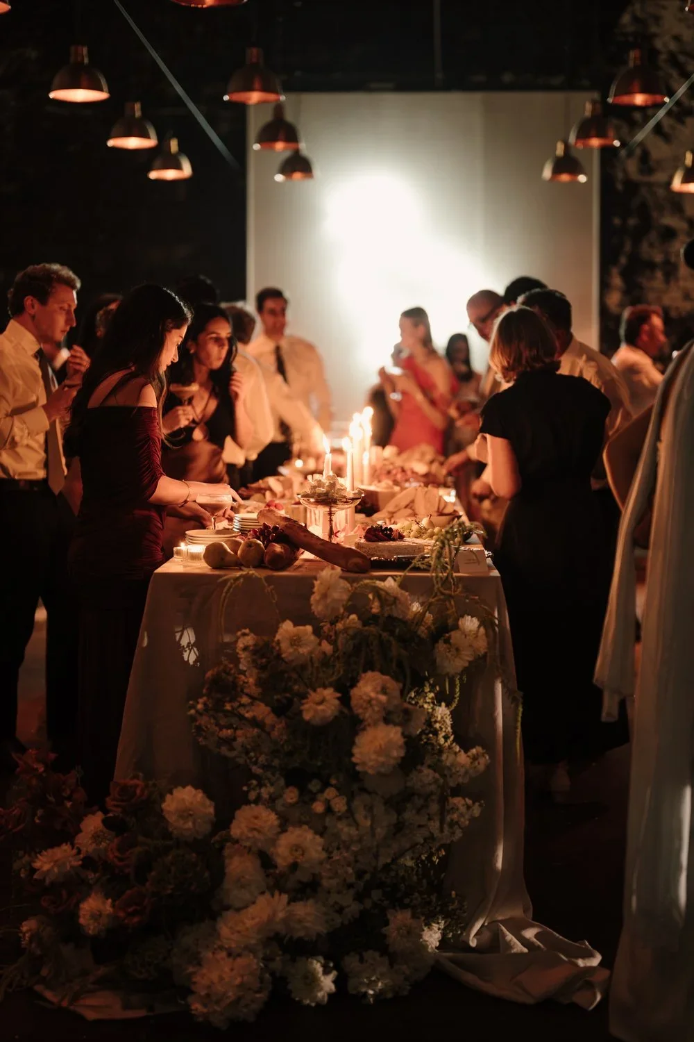 A group of people gathered around a decorated dessert table at night designed and styled by Alex Morabito on the Mornington Peninsula