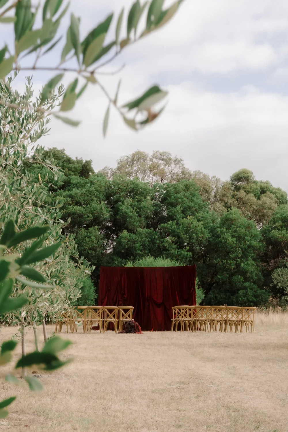 Outdoor wedding ceremony set up and styled by Alex Morabito for Ever After Effect with a red velvet curtain backdrop/draping on a private property in Main Ridge.