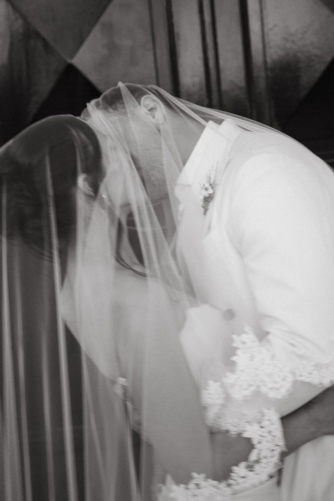 A groom and bride facing each other closely, sharing an intimate moment behind a veil.