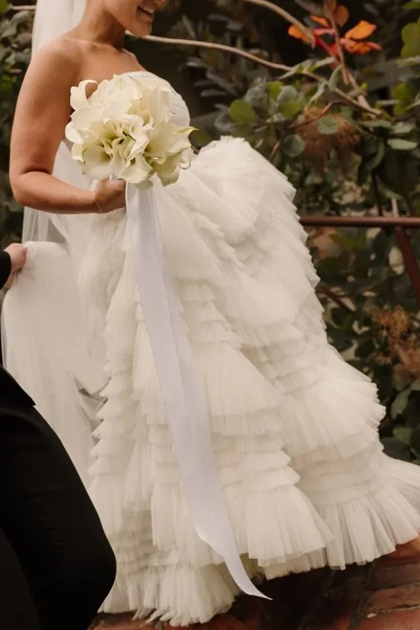 Bride in a white ruffled wedding gown holding a bouquet of white flowers at her wedding on the Mornington Peninsula, planning and on the day coordination service by Ever After Effect.