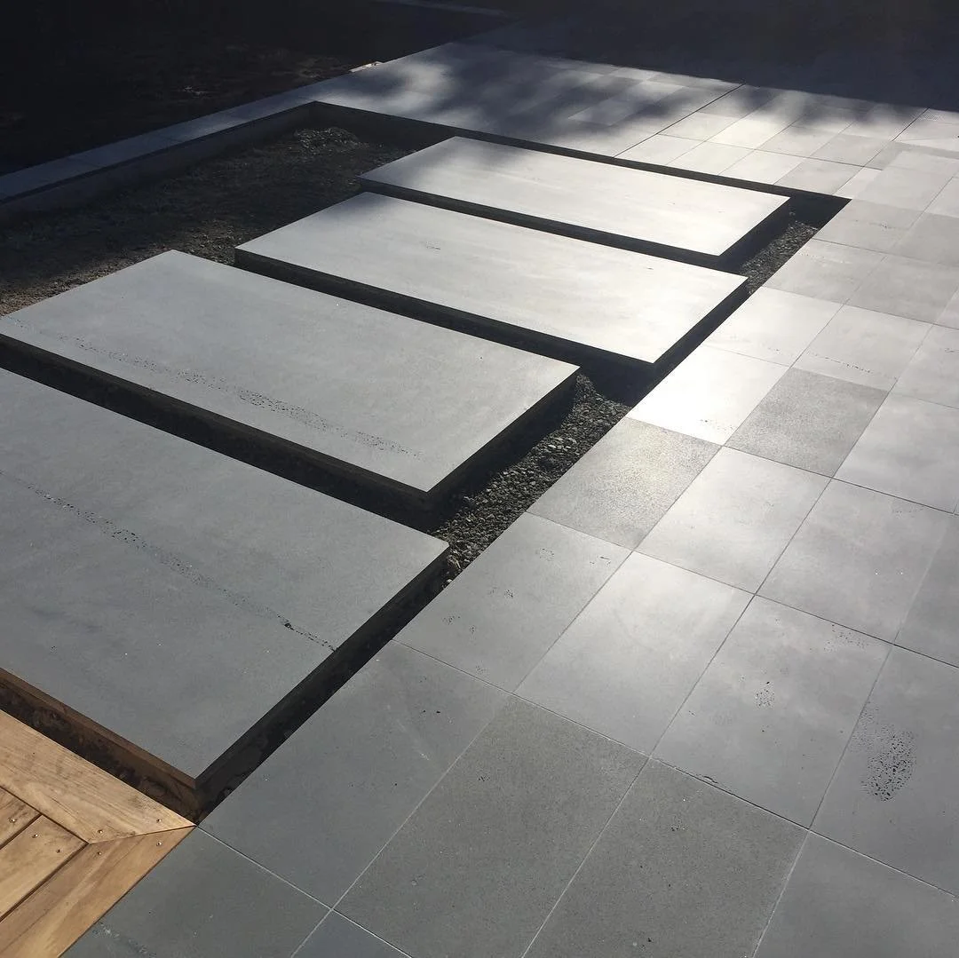 Several large natural stone paving slabs are arranged in a step formation, with a surrounding paved area