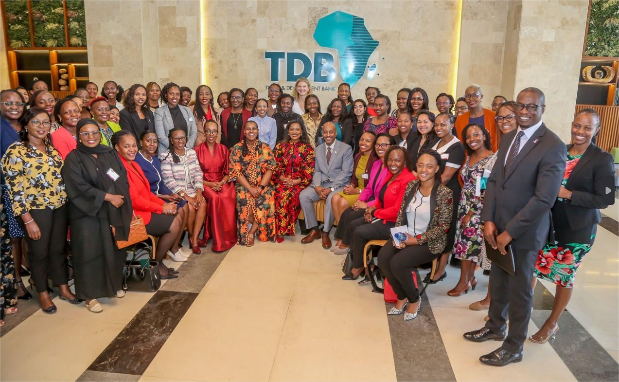 Group of women and men posing for a photo at the African Development Bank headquarters, with the bank's logo in the background.