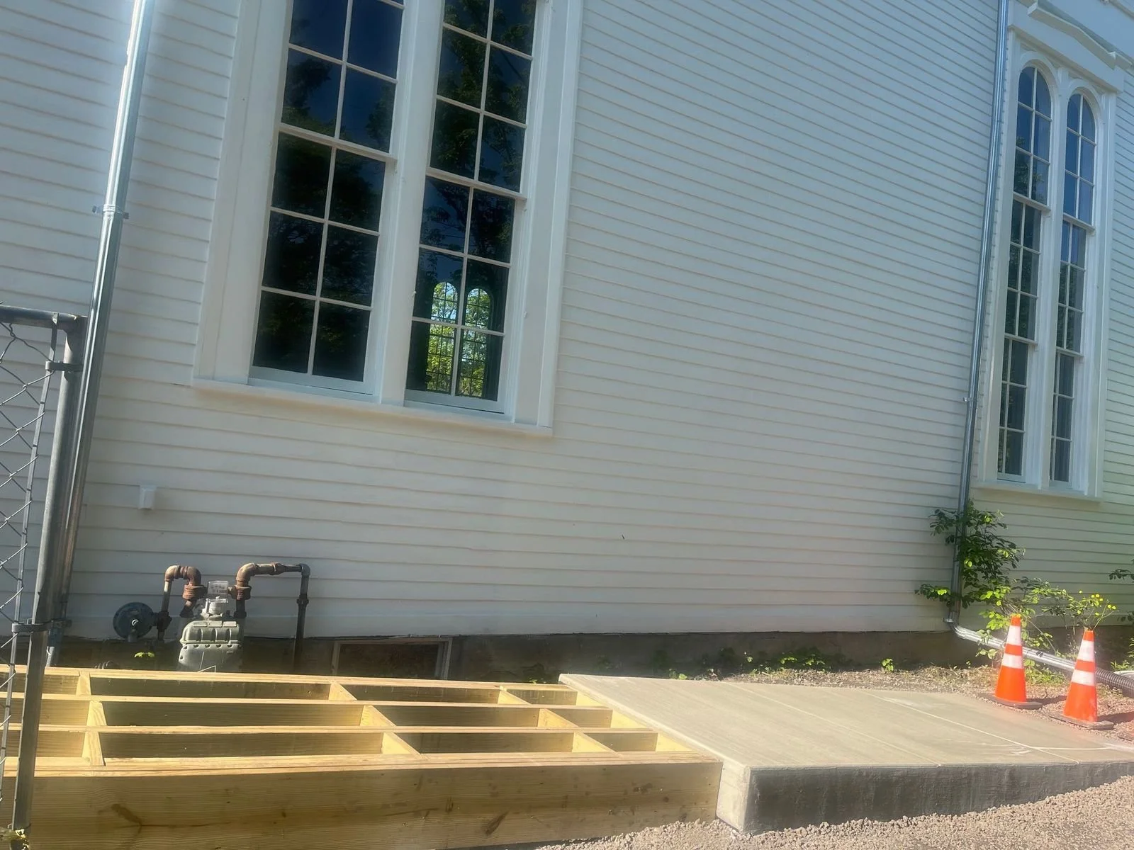 Exterior of TCFA with large windows, construction materials, and safety cones nearby, indicating ongoing building or renovation work.