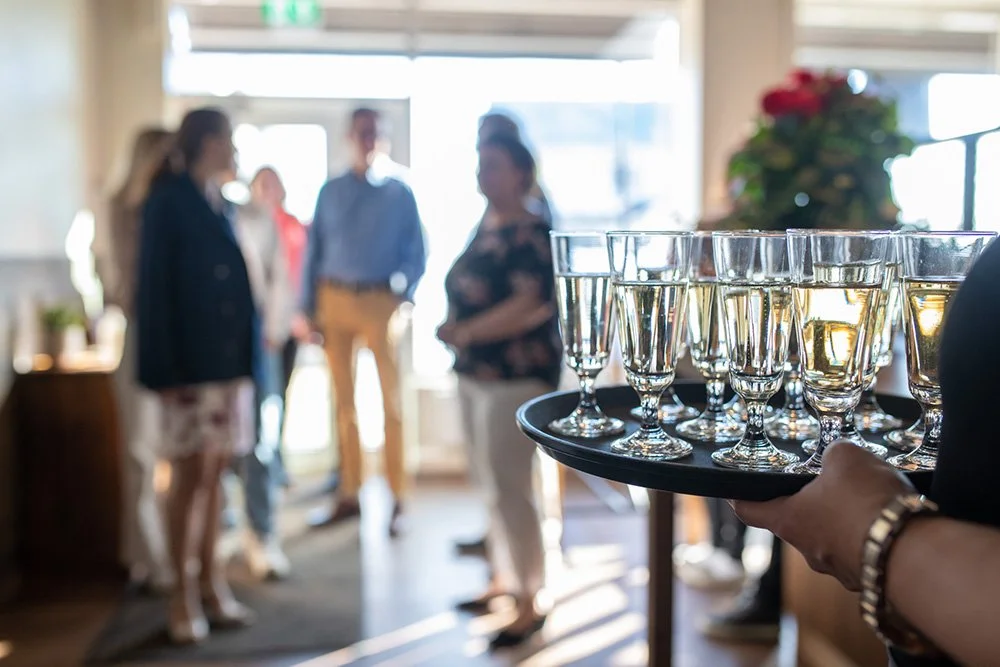 Henkilö pitelee tarjotinta, joka täynnä kuohuviinilaseja.