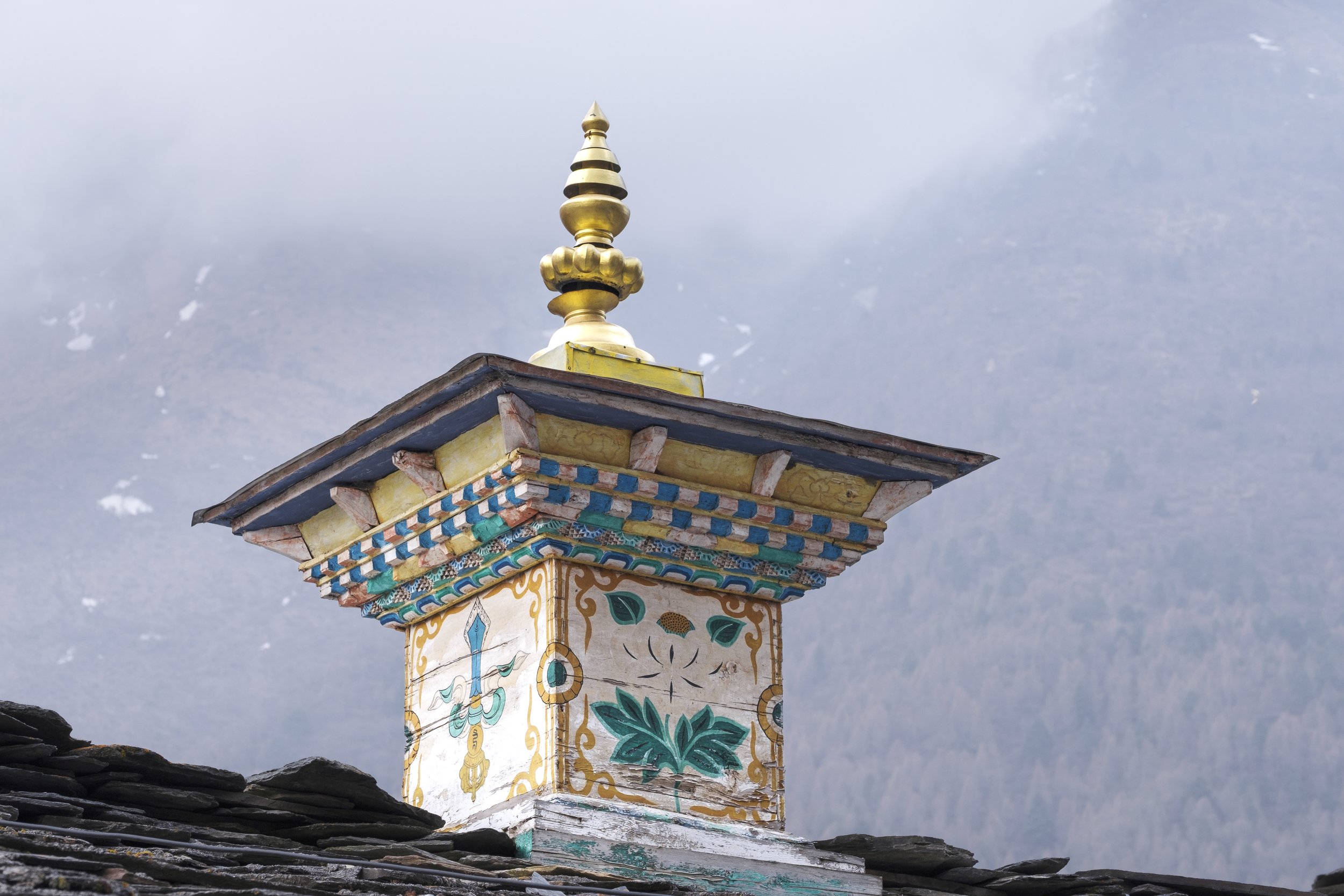 Painted Buddhist shrine with decorative patterns on a slate roof in Tsum Valley, Nepal.