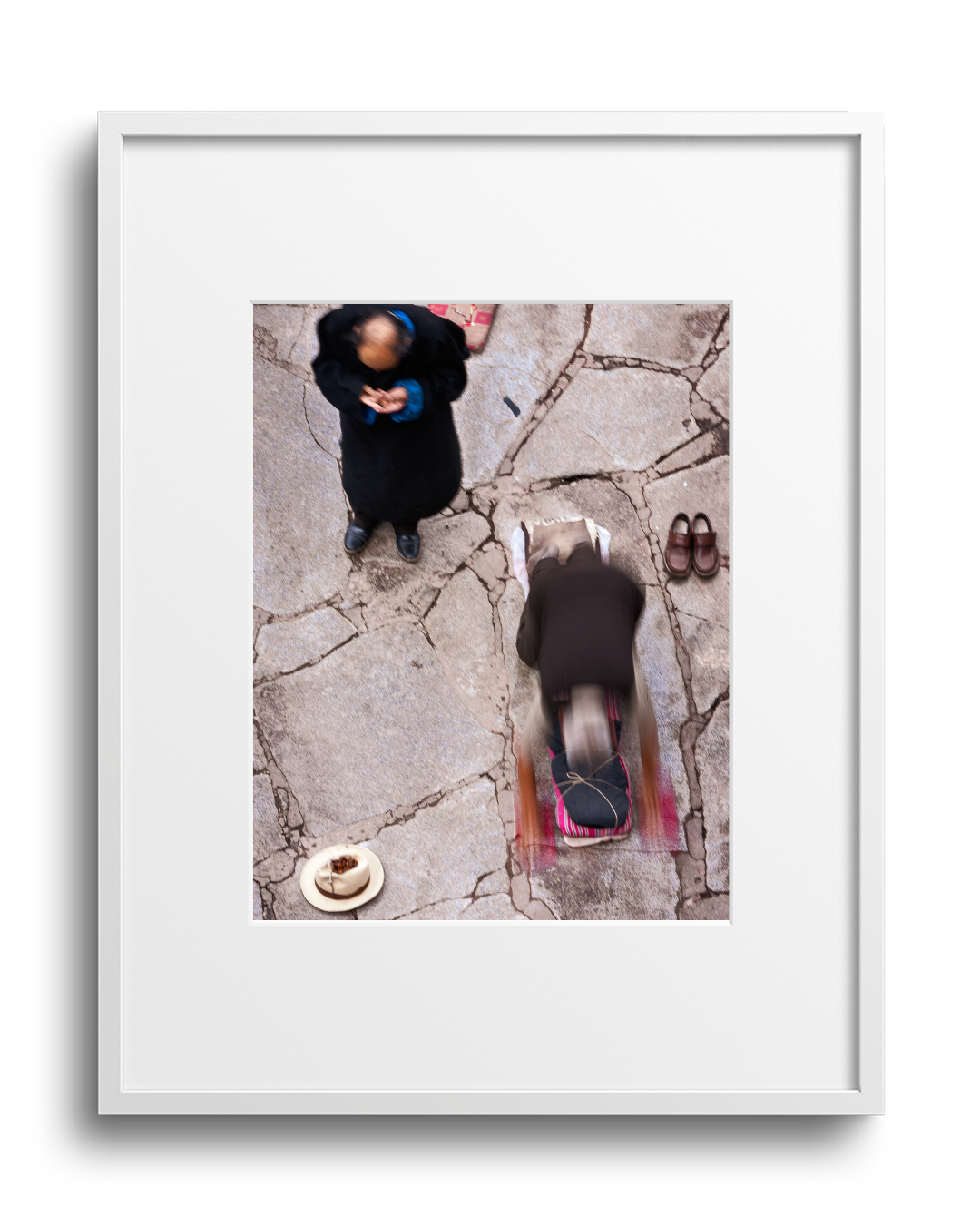 Overhead view of a person walking on cracked pavement with a backpack, another person standing nearby, a plate with a chocolate dessert, and a pair of brown shoes.