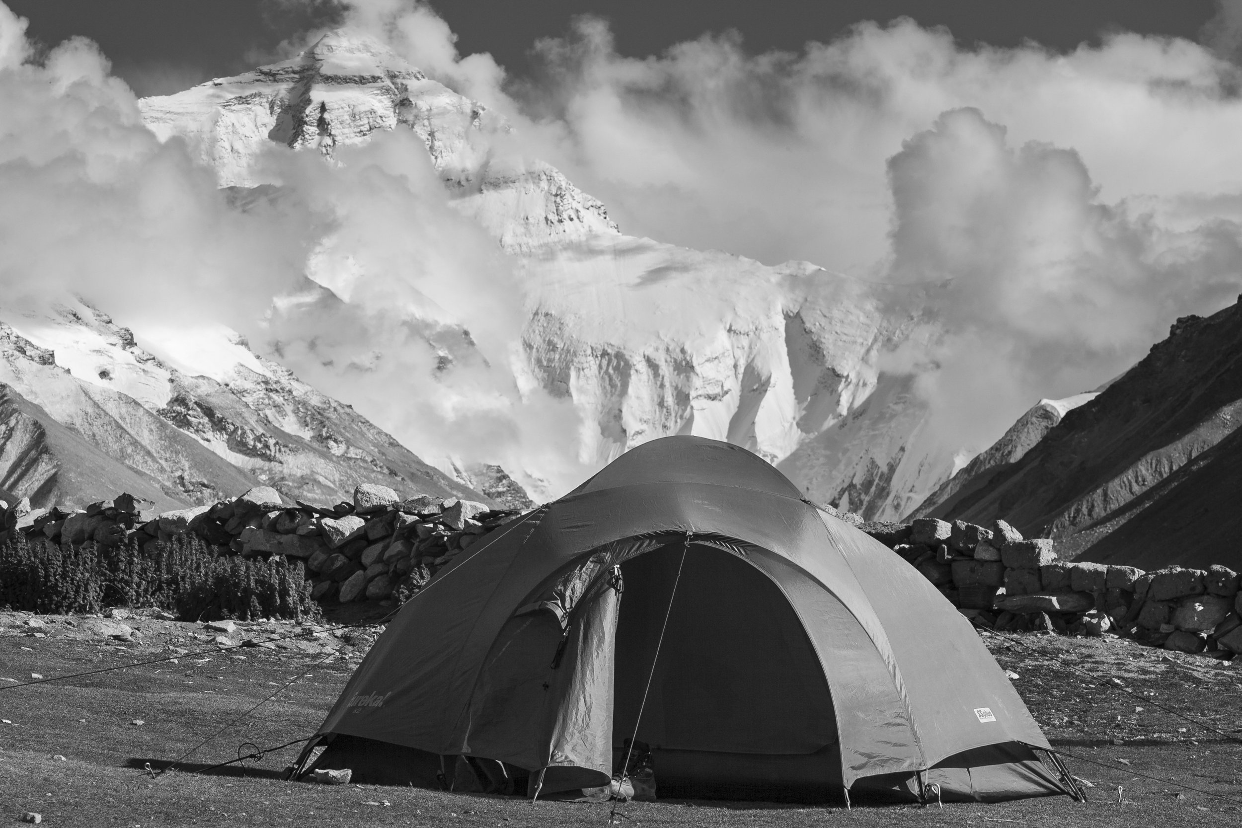 Isolated tent pitched on an open plateau surrounded by rolling mountains in Tibet.