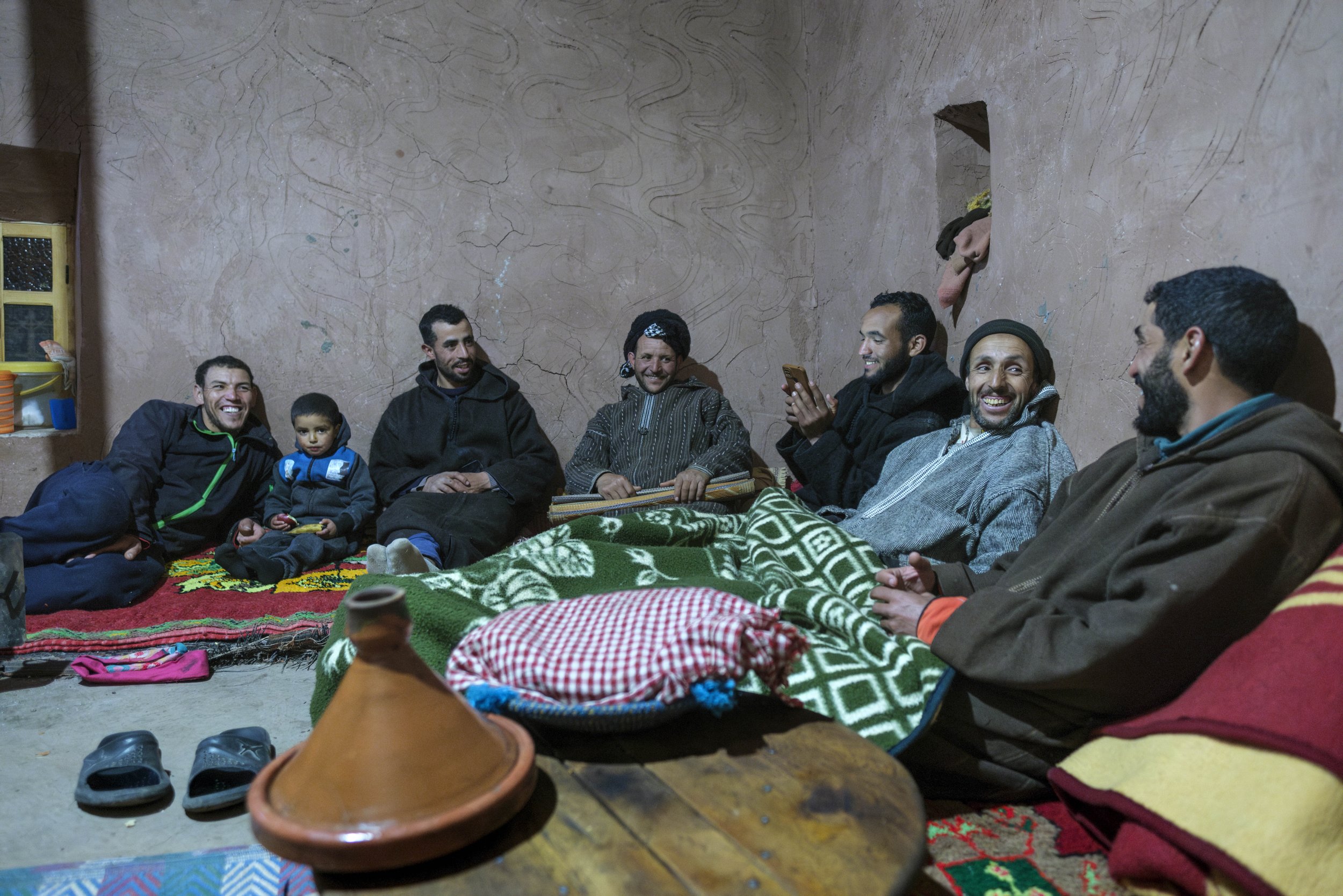 Men and a child gathered inside a traditional home in the Aït Bouguemez Valley of Morocco’s High Atlas Mountains.