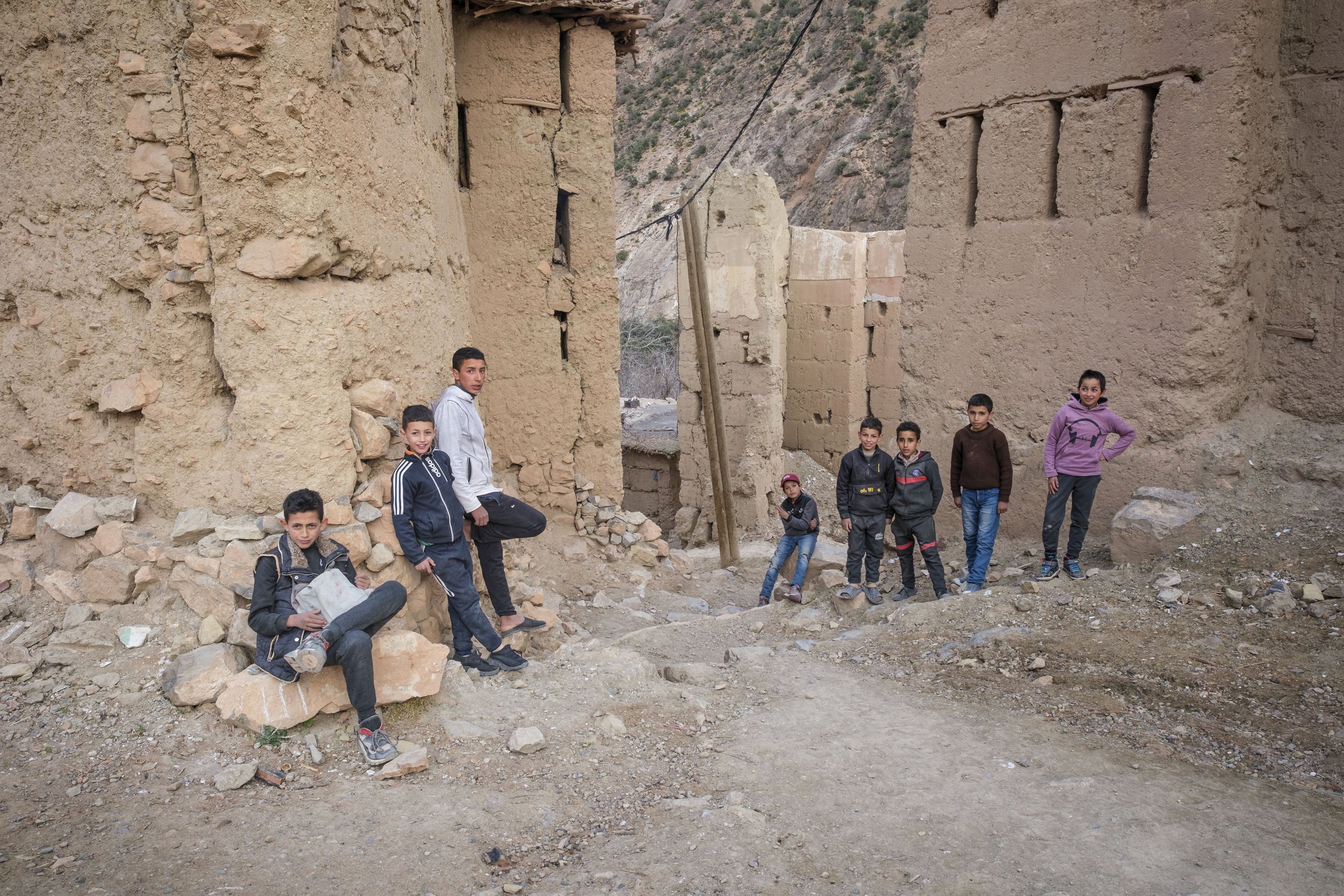 Children standing among adobe houses and narrow paths in a mountain village in the High Atlas of Morocco.