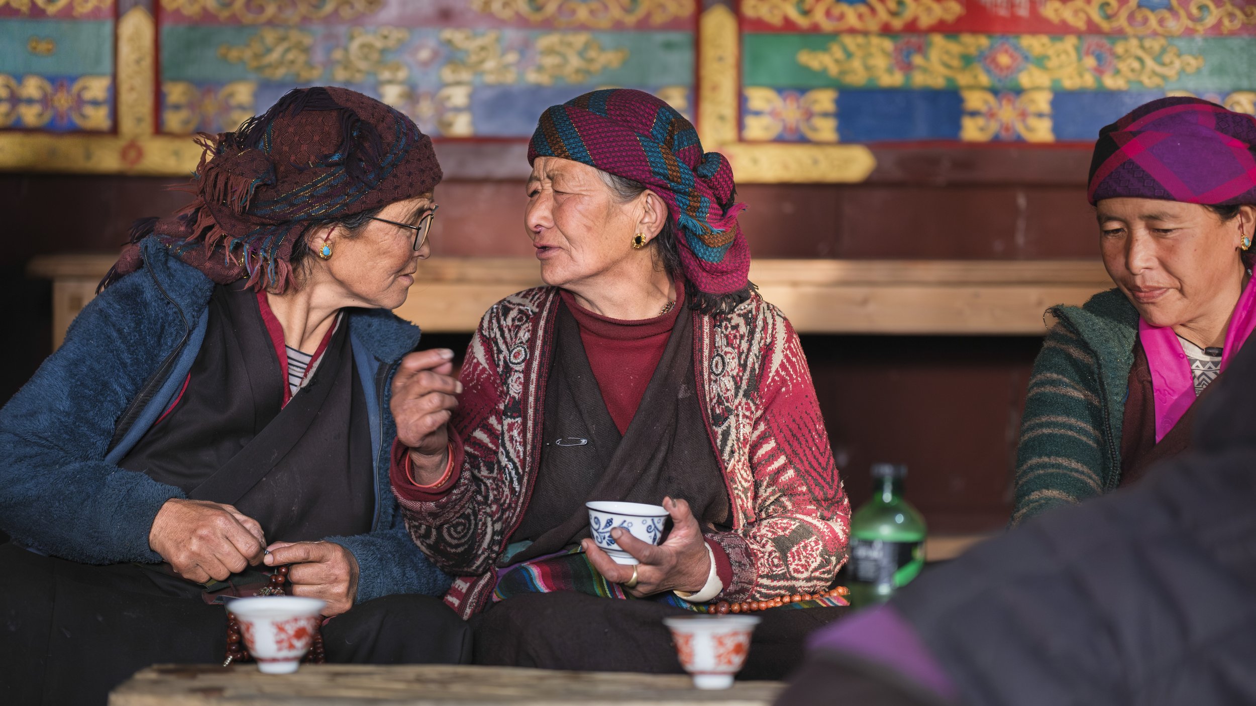 Women sharing tea and conversation inside a community monastery in Tsum Valley, Nepal.