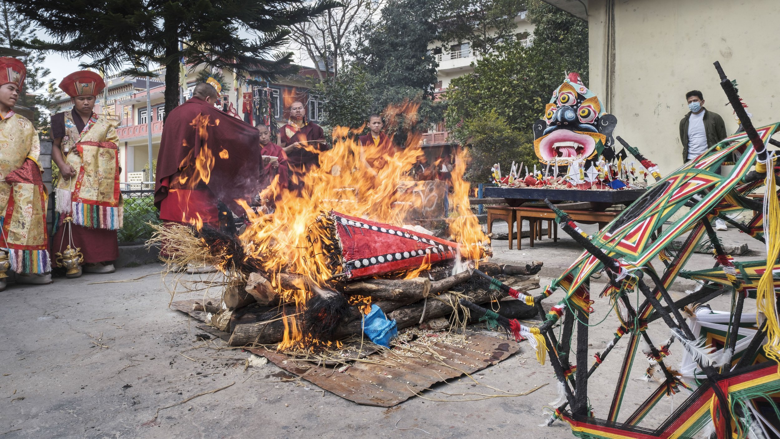 Monks and ritual objects surrounding the burning Mahakala torma during Gutor Chenmo ceremony in Boudhanath, Kathmandu.