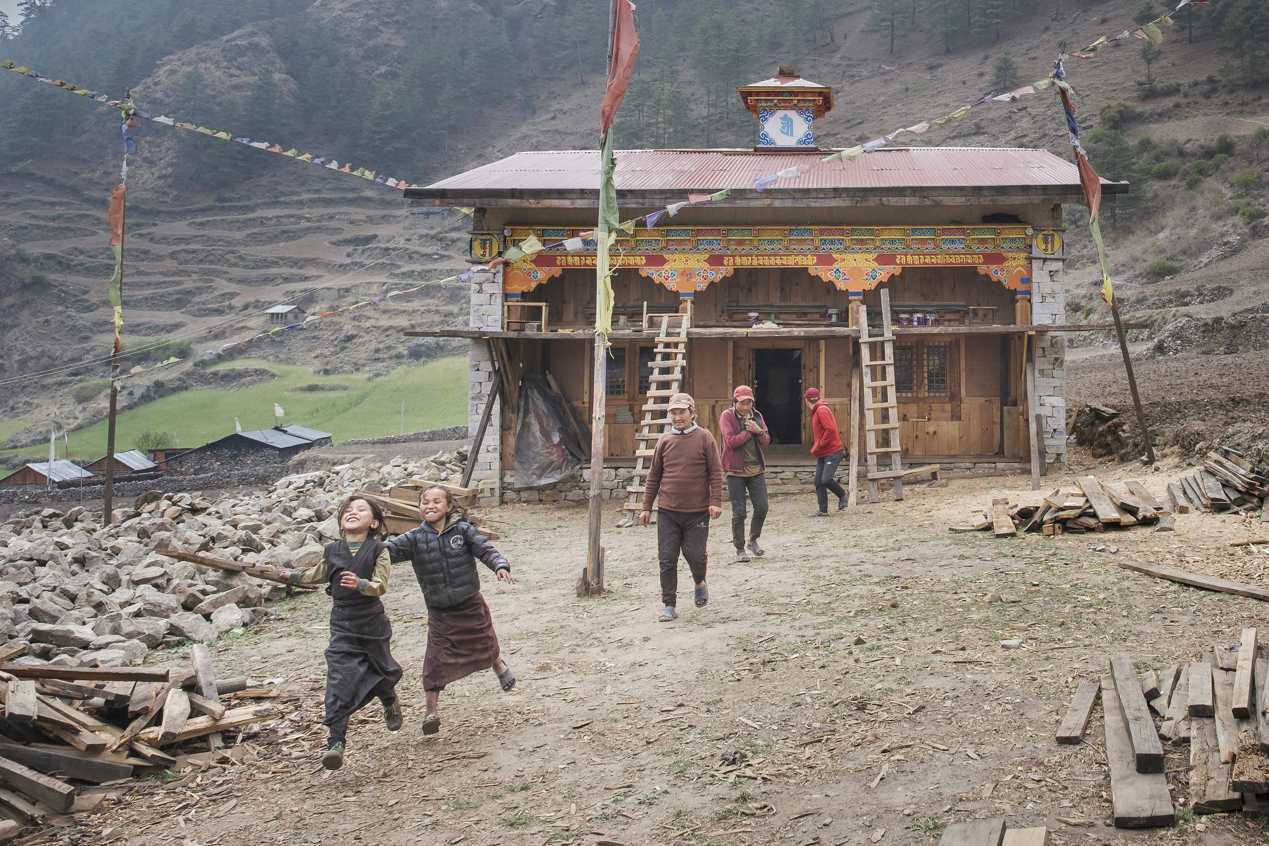 Children running in a village courtyard near a monastery in Tsum Valley, Nepal.