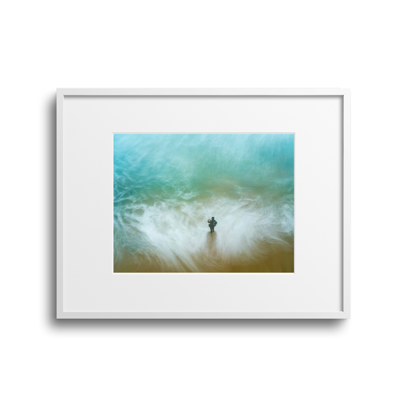 A framed photo showing a person standing on a sandy beach, fishing as waves wash around them under cloudy skies.