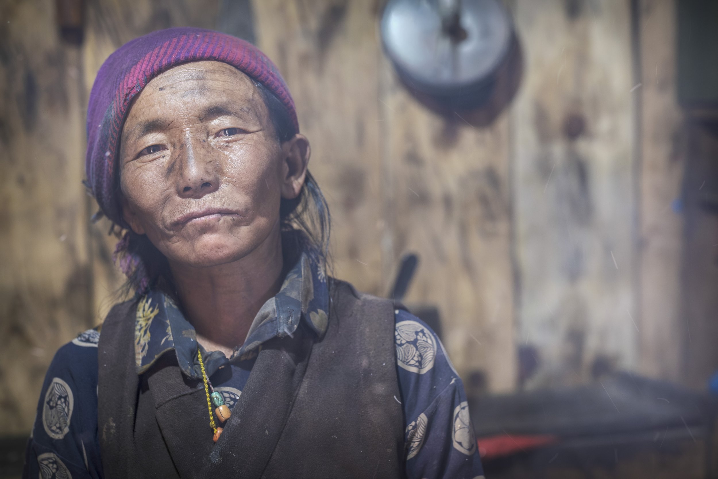 Pema Doma, Sonam's mother, sits in her kitchen in Chumchet. While her son manages the guesthouse, she continues the steady domestic work that sustains it, cooking, tending the hearth, and holding together the balance of village life and home. Tsum Va