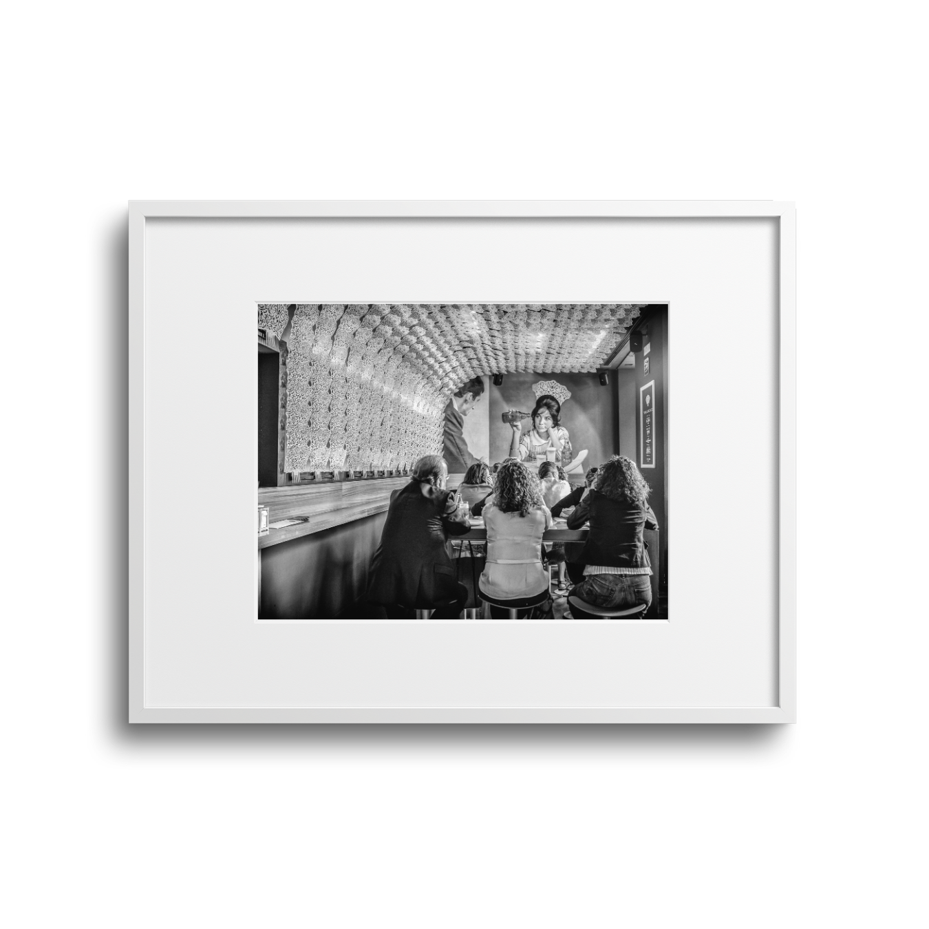 Group of women seated at a table watching a presentation or performance in a venue with decorative interior.