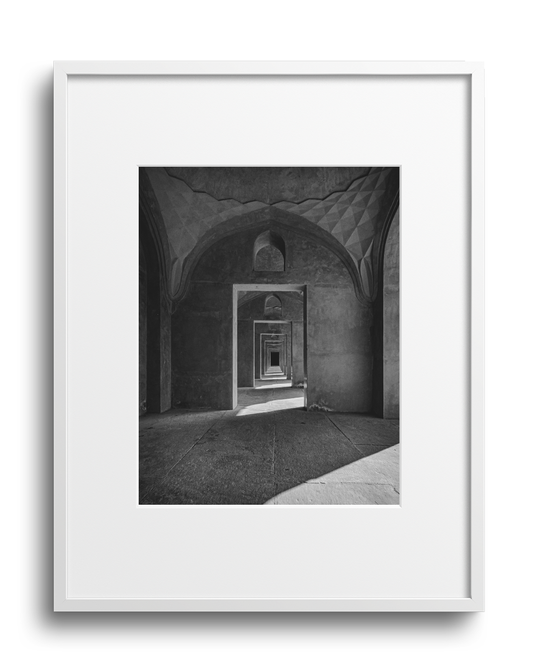 Black and white photograph of an architectural tunnel with repeating arches and geometric patterns, creating a sense of depth.