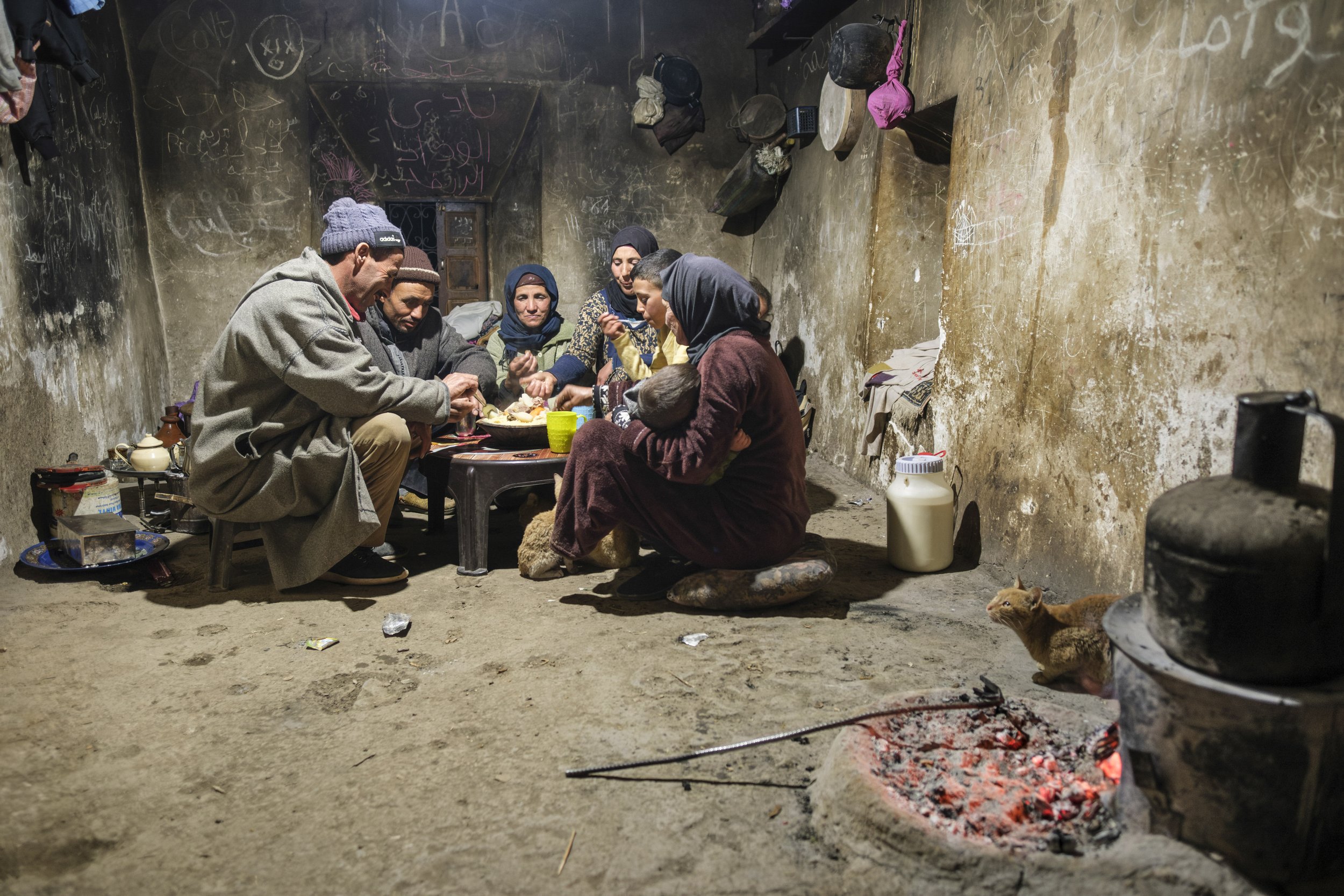 Family sharing a meal inside a traditional home in the Aït Bouguemez Valley in Morocco’s High Atlas Mountains.
