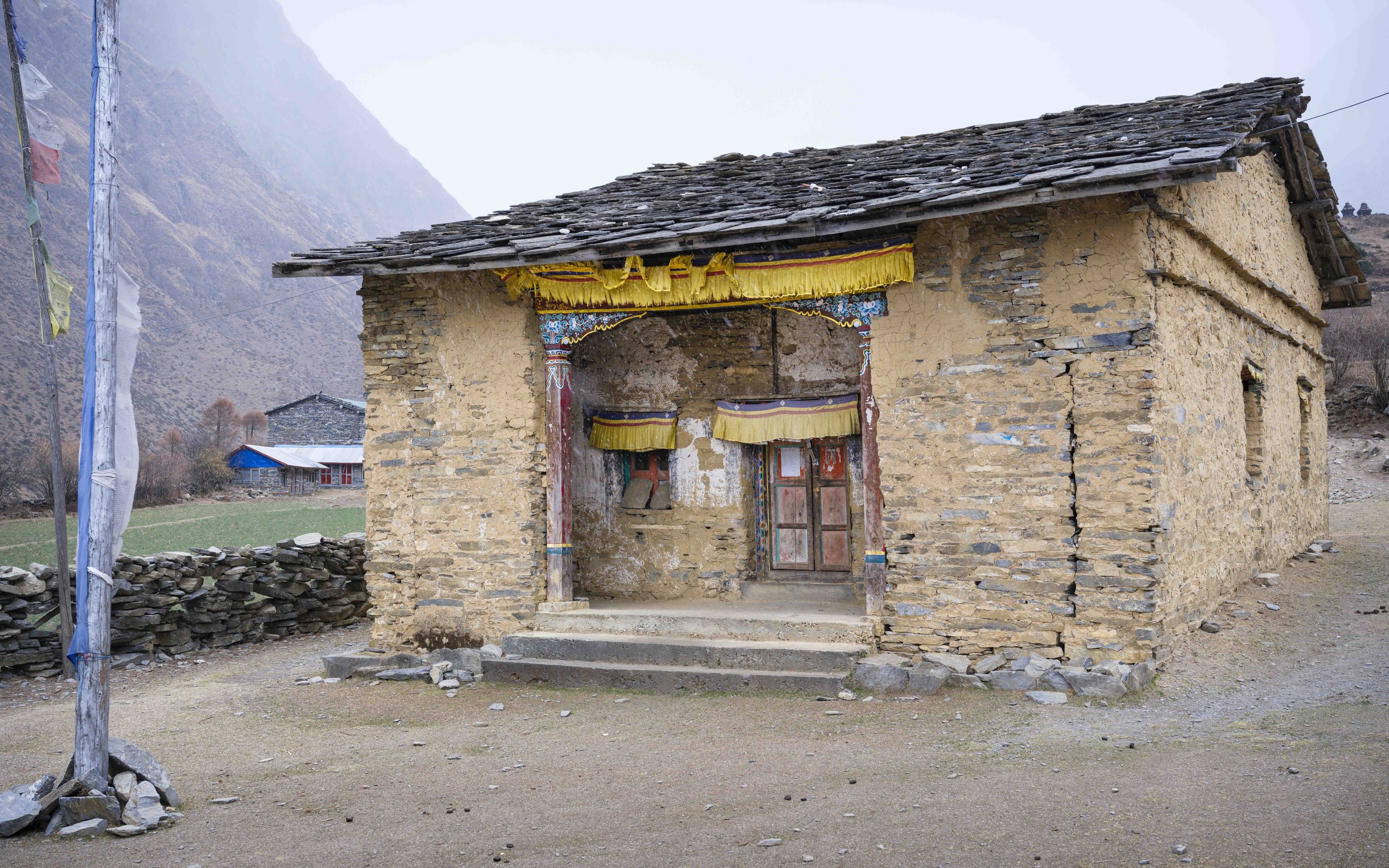 Small stone monastery building with painted doorway in a remote village in Tsum Valley, Nepal.