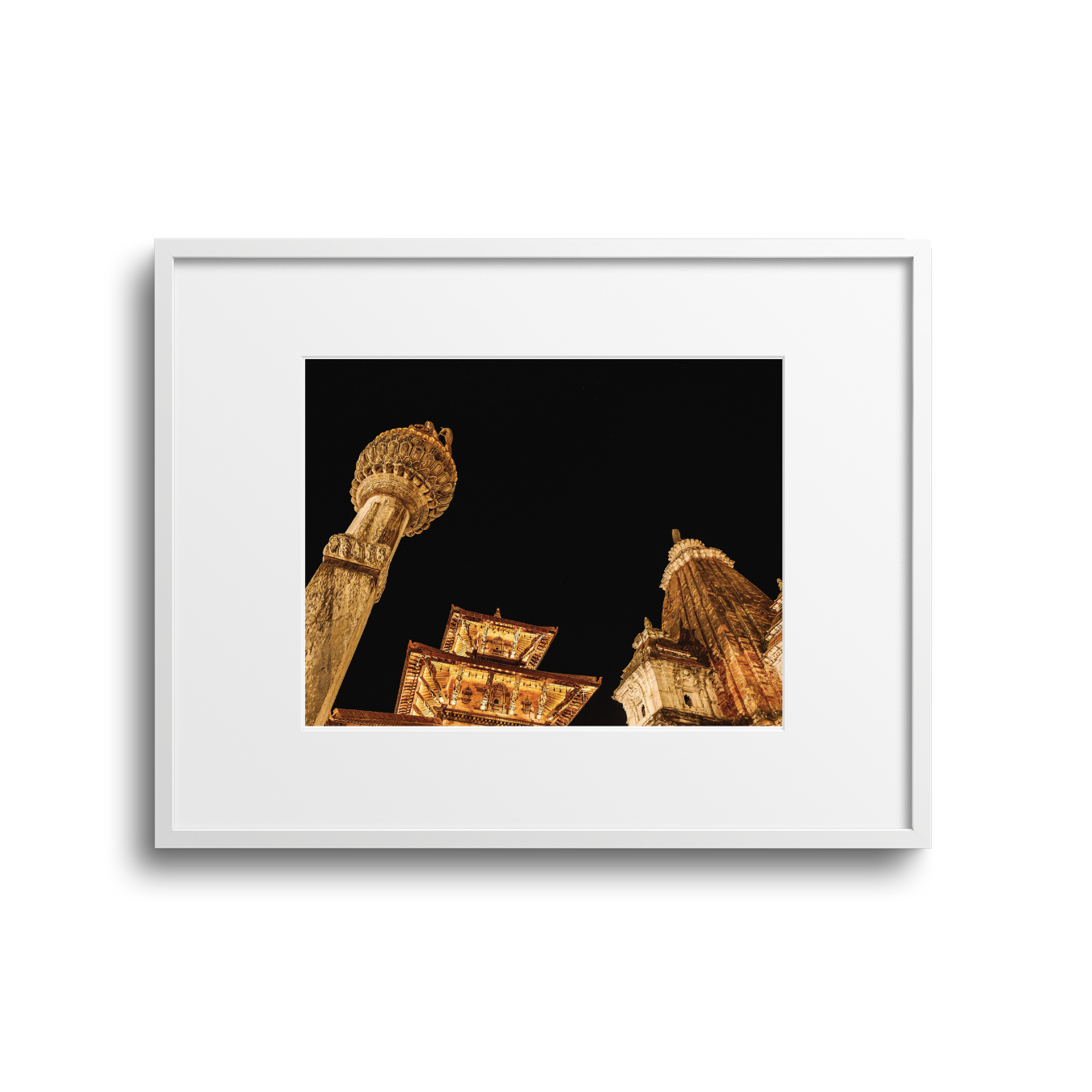 Nighttime view of ornate temple architecture and columns illuminated against a dark sky.