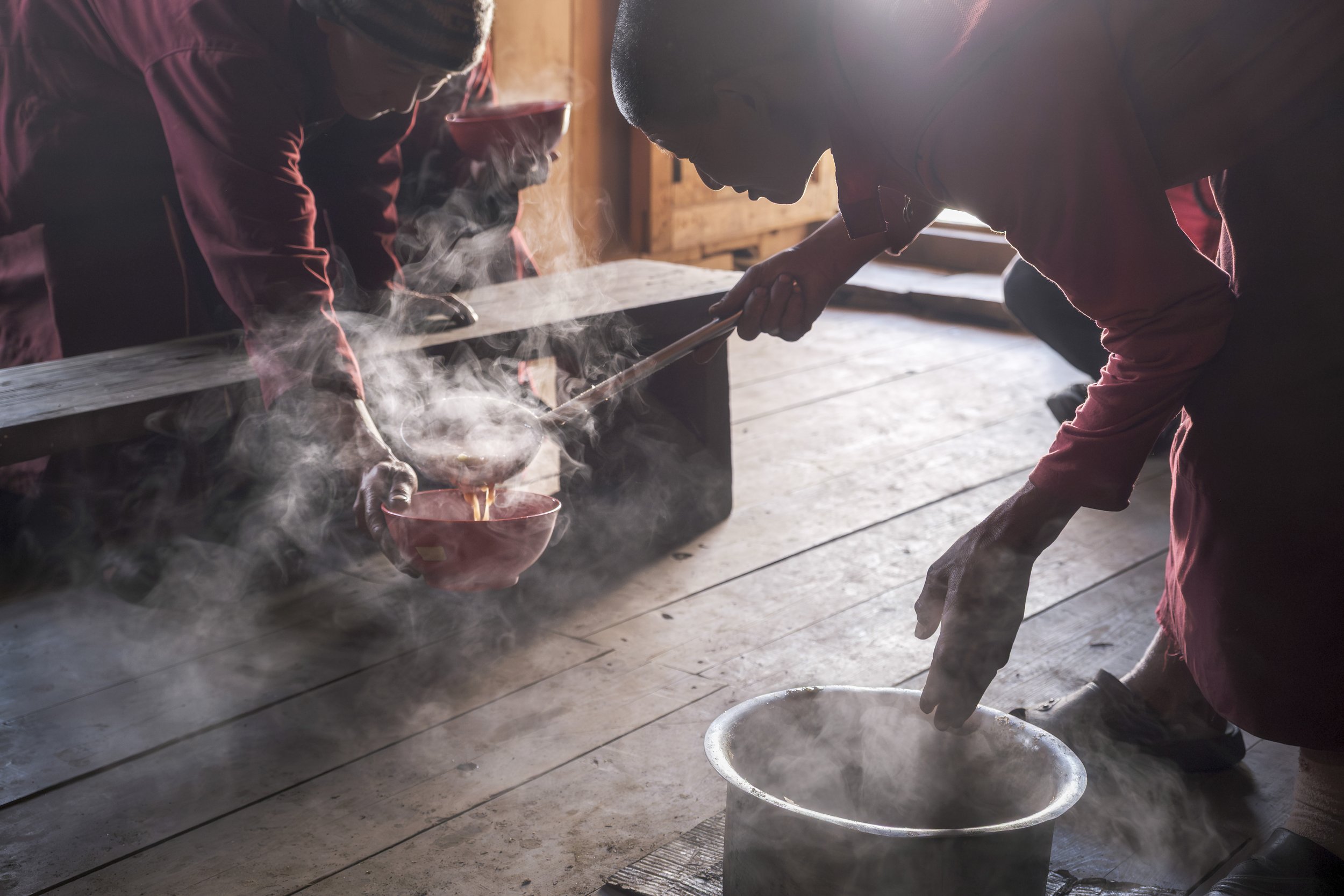 In the common kitchen in Gompa Lungtang, steam rises as Ani Hissi pours khole, a thin soup of tsampa, into Ani Tsering’s bowl. This simple meal marks the daily life of the nunnery, repeated with little change, except on rare occasions like Losar, the